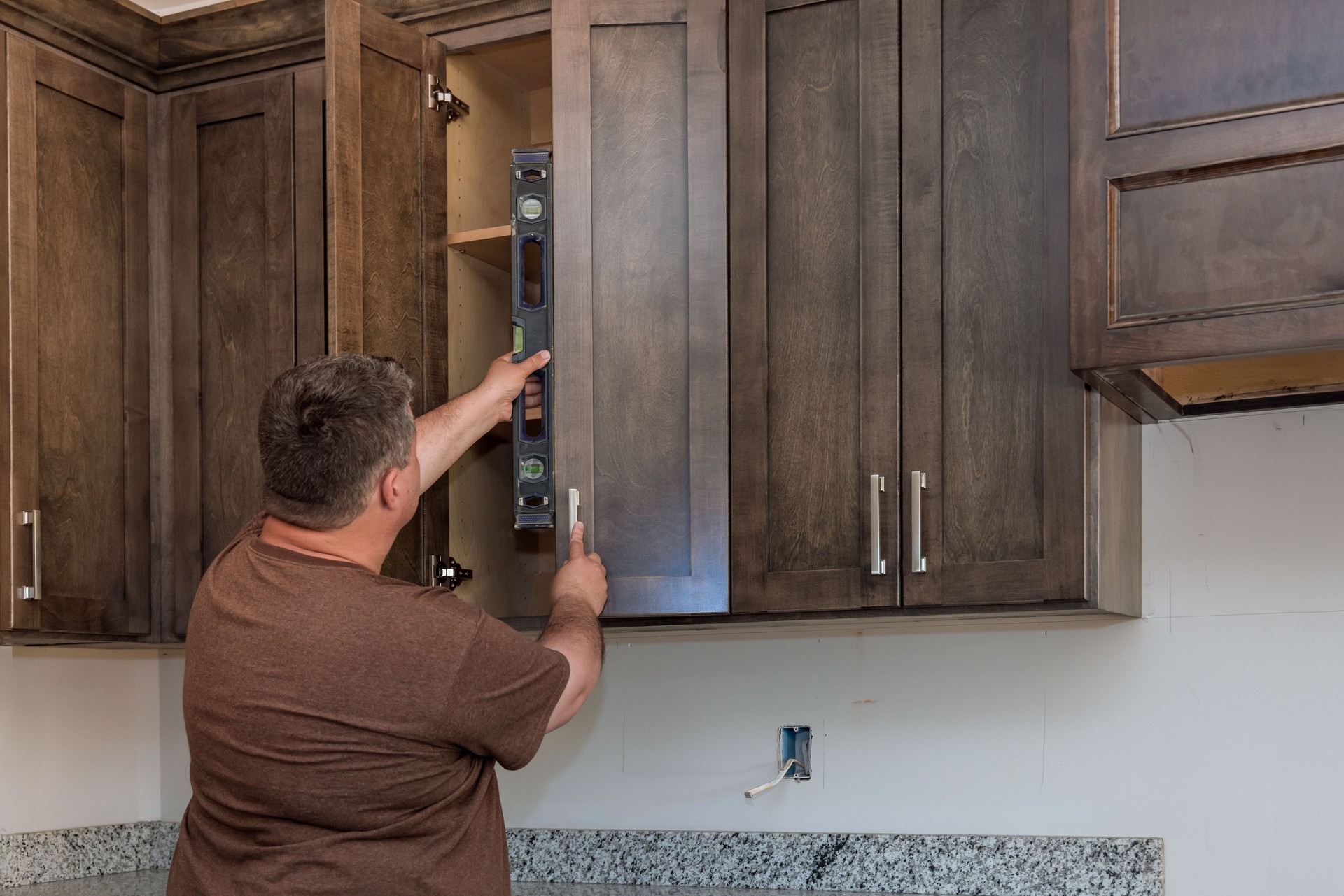 During assembling new kitchen cabinets, supervisor checks quality of installation using a level measurement tool